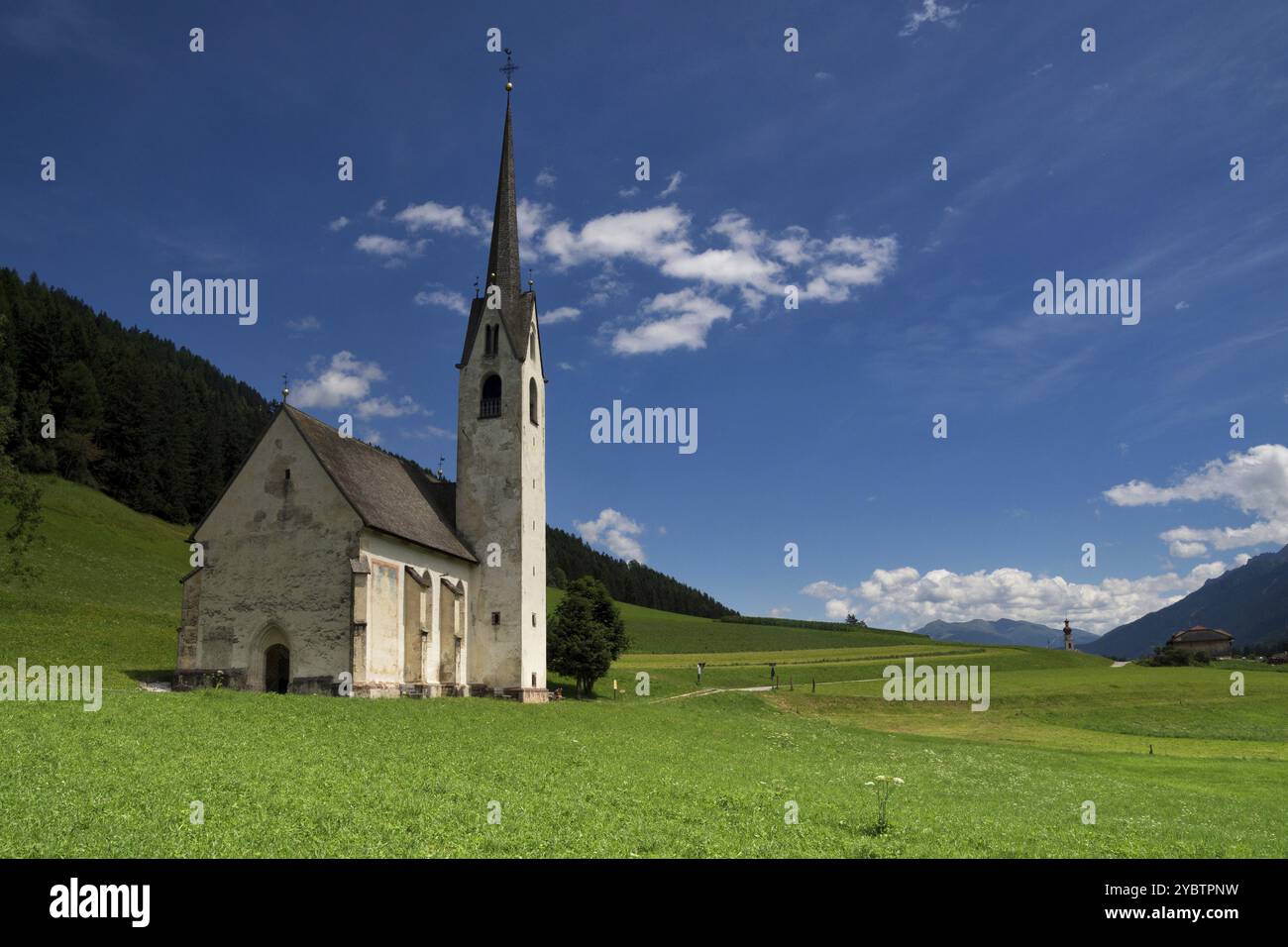 La chiesa di Santa Magdalina nei pressi di Villabassa circondata da un prato verde nelle Dolomiti italiane Foto Stock