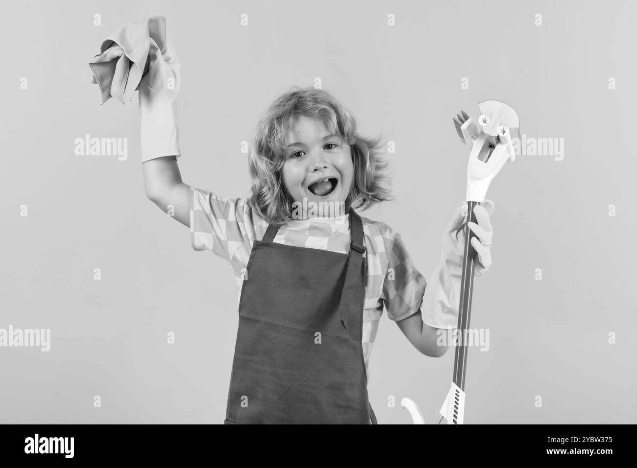 Bambino aiutare a pulire. Bambino che fa il lavoro di casa che si diverte. Studio isoalted ritratto di cameriera bambino con mop bagnato piatto su sfondo giallo. Foto Stock