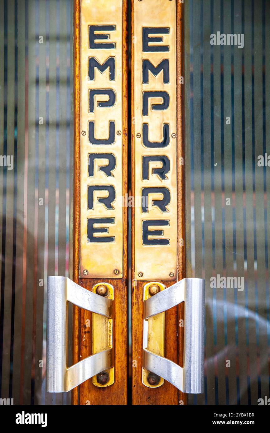 Un dettaglio ravvicinato di una maniglia per porta vintage con la parola "Empurre" a Lisbona, Portogallo. Le texture in legno e metallo aggiungono un fascino antico. Foto Stock