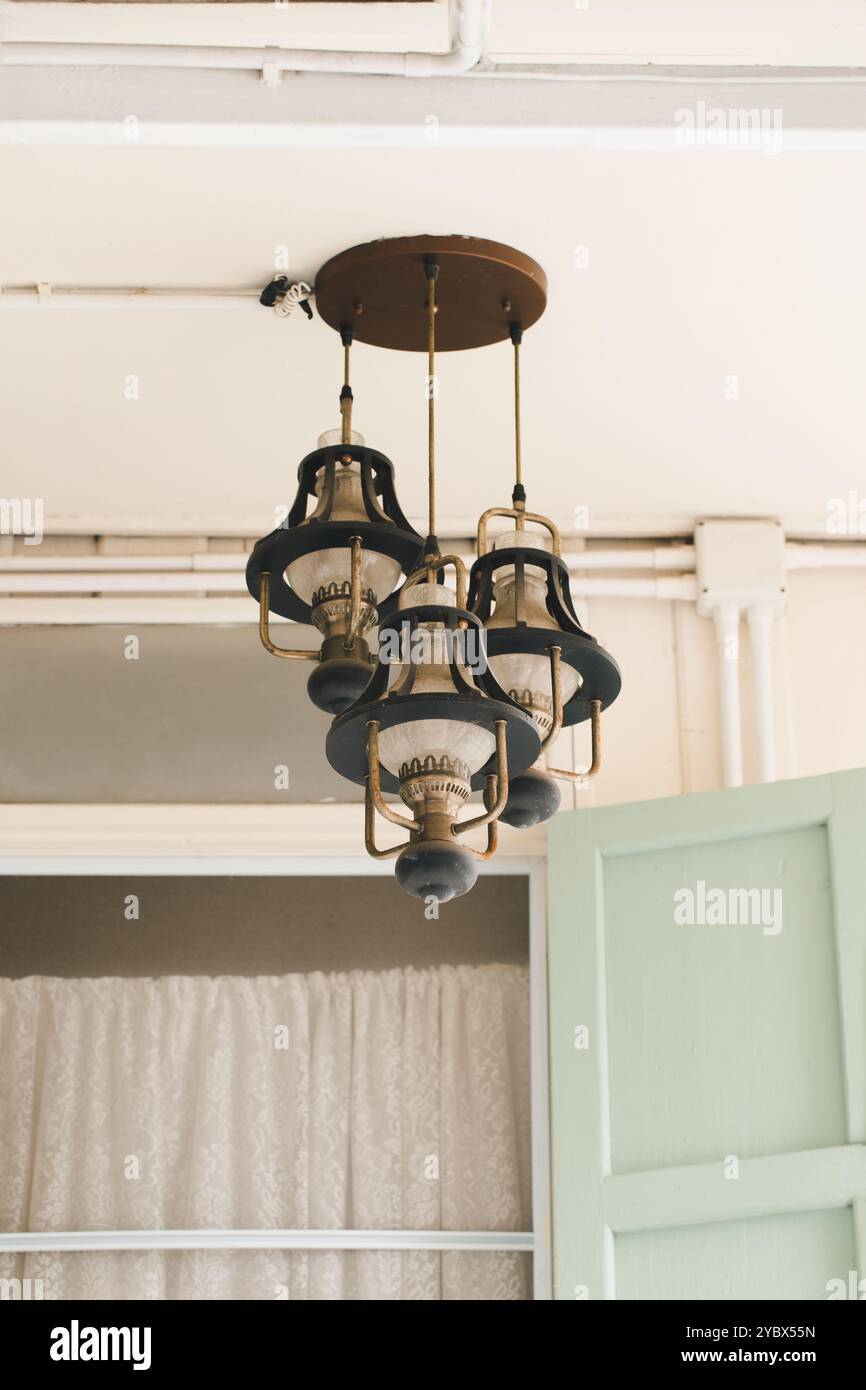 Una lampada vintage, sospesa sul soffitto, aggiunge un tocco di eleganza classica alla stanza. Il design intricato e la patina invecchiata della lampada mettono in risalto i Foto Stock