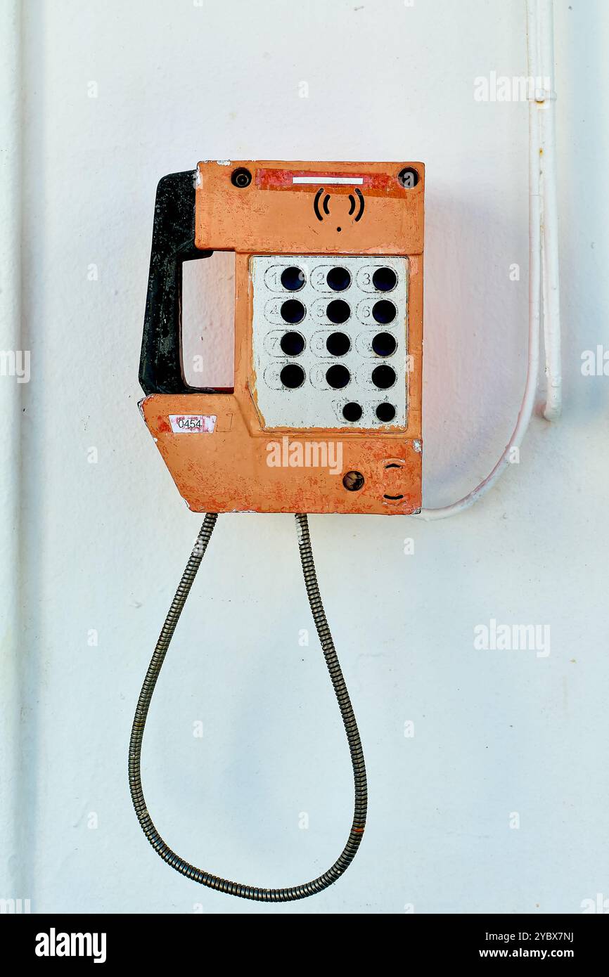 Un telefono vintage montato su una parete bianca a bordo di una nave, che mostra la miscela di tecnologia di comunicazione classica in un ambiente nautico. Perfetto per Foto Stock