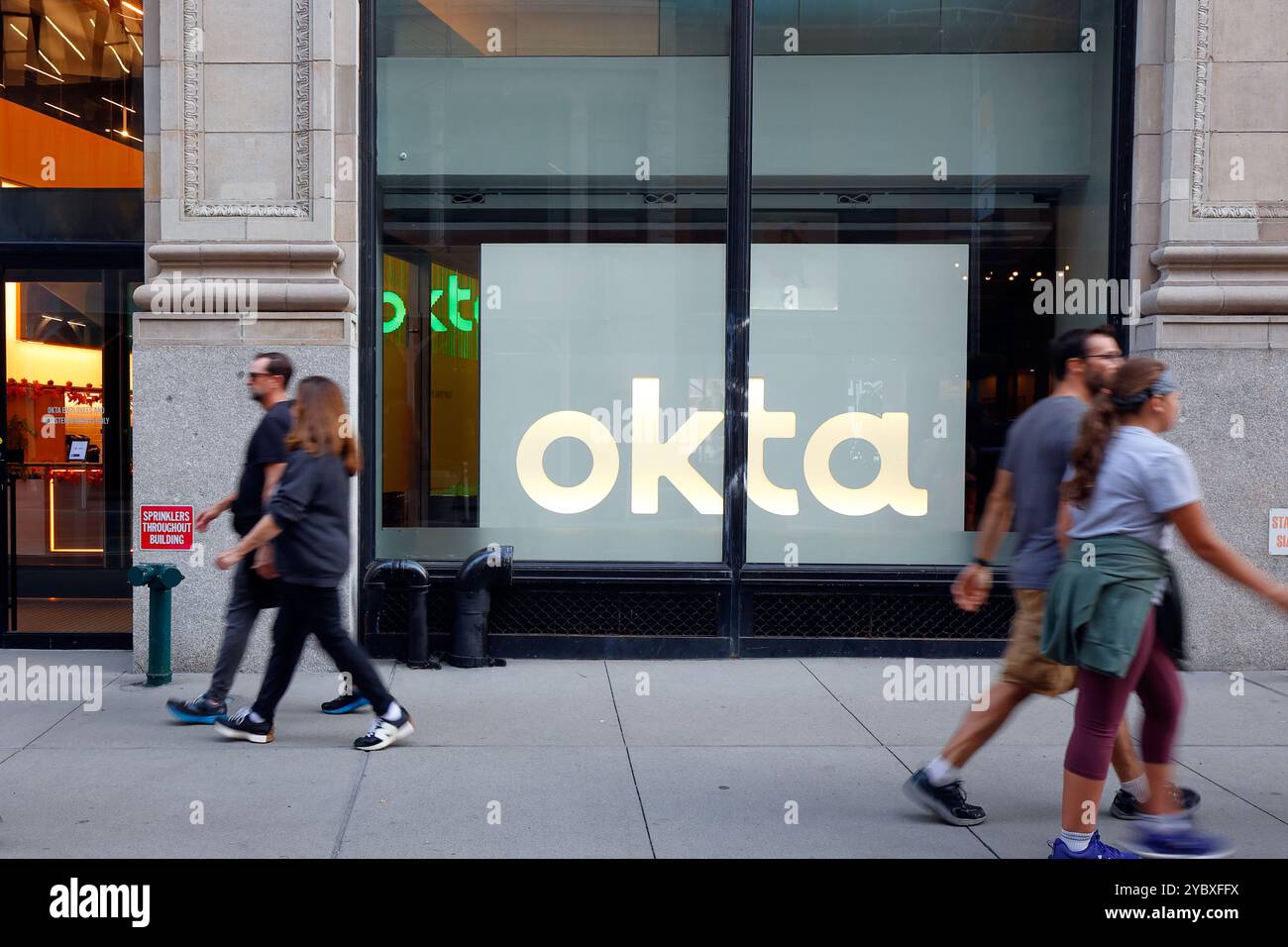 Persone che camminano oltre l'Okta Experience Center, 920 Broadway, New York City, nel quartiere Flatiron di Manhattan. Foto Stock