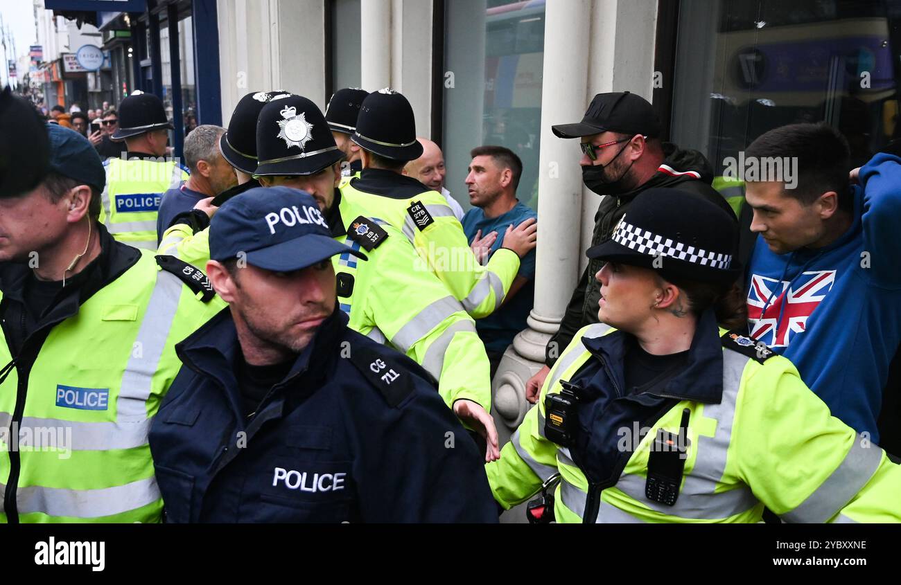 Brighton Regno Unito 7 agosto 2024 - Un commerciante locale che lavorava nelle vicinanze viene coinvolto nelle proteste ed è protetto dalla polizia come protesta antirazzista contro le recenti manifestazioni di estrema destra in tutto il Regno Unito . Ci sono state rivolte razziali dopo l' omicidio di 3 bambini a Southport a luglio : Foto Stock