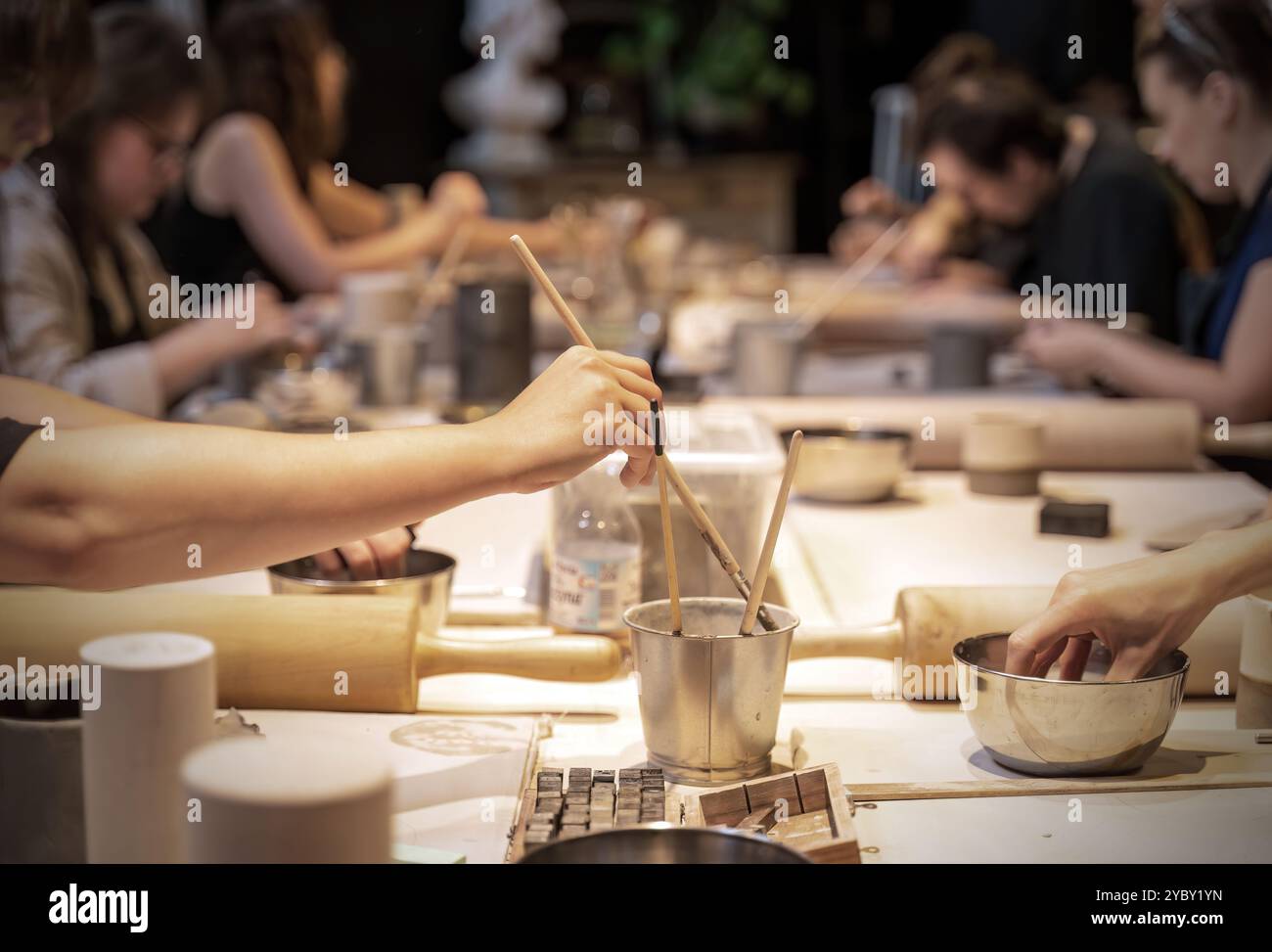 Un gruppo di persone impegnato in un laboratorio di ceramica, incentrato sulla produzione di ceramiche e sulla creatività in un ambiente collaborativo. Vari strumenti e accoppiamenti Foto Stock