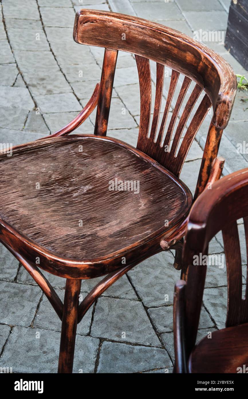 Un paio di sedie rustiche viennesi in legno intemperie collocate in un caffè di strada. Circondata da lussureggianti piante in vaso, la scena trasuda calore e relax. Foto Stock