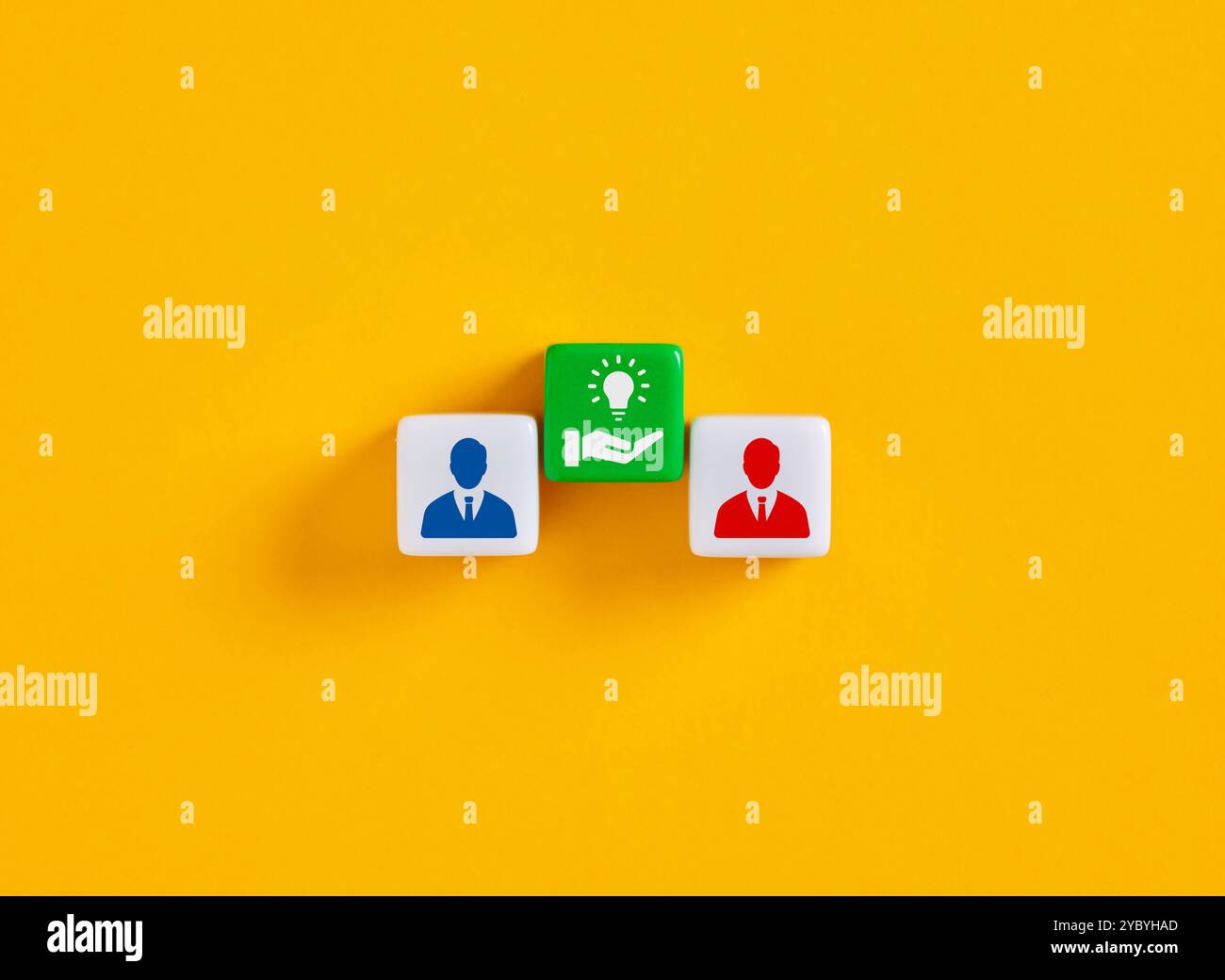 Condivisione di idee. Tre cubi che rappresentano due uomini d'affari che condividono una grande idea per la loro attività su uno sfondo giallo Foto Stock