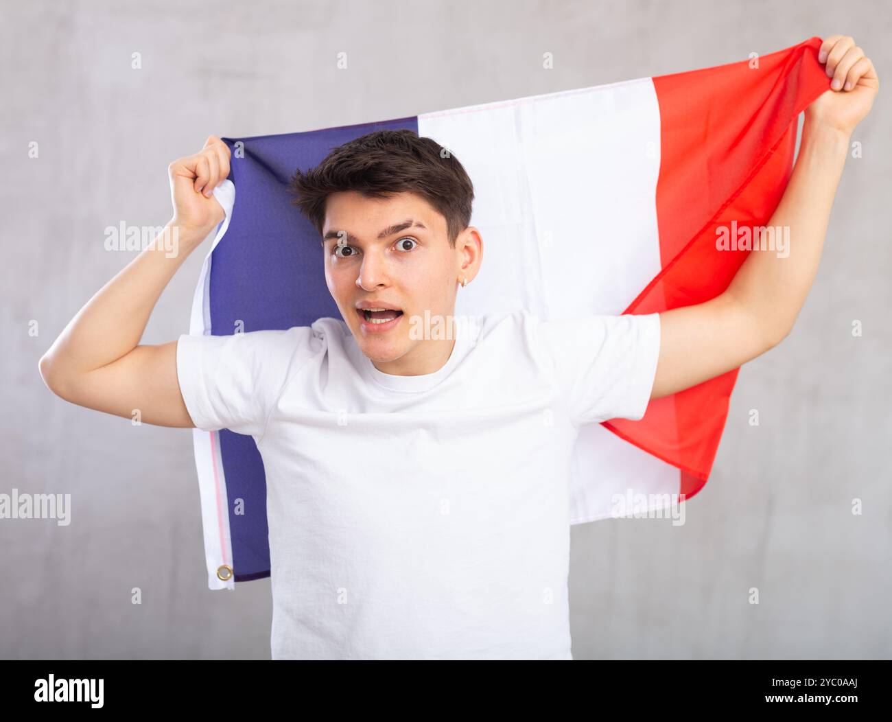 Eccitato, attivo spettatore maschile detiene bandiera nazionale della Francia in mani e canti slogan popolare Foto Stock
