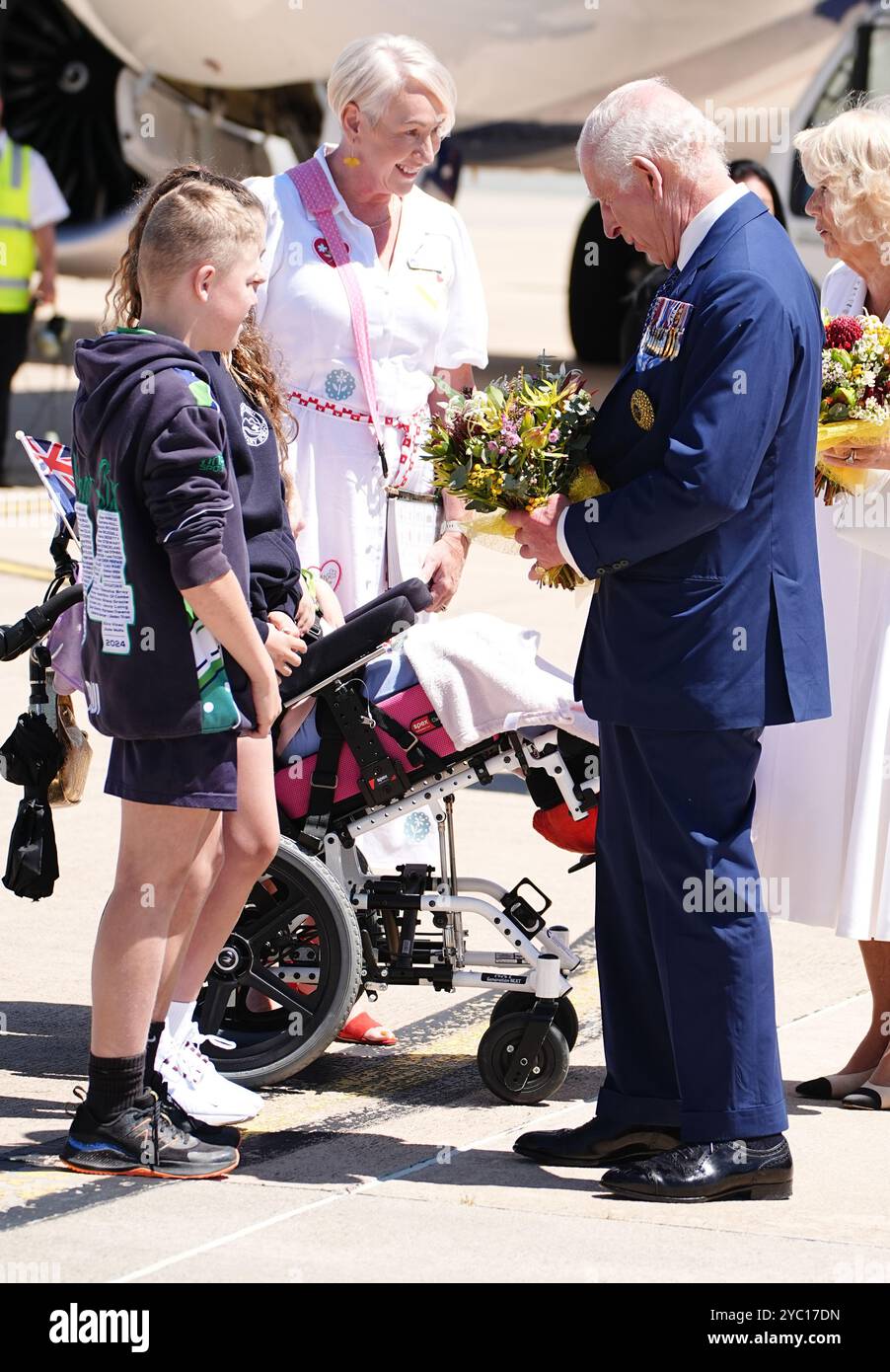 Re Carlo III parla con due scolari presentando fiori per la festa di benvenuto ufficiale australiana all'aeroporto di Canberra il secondo giorno della loro visita in Australia e Samoa. Data foto: Lunedì 21 ottobre 2024. Foto Stock