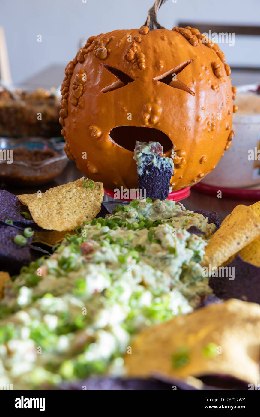 Una zucca dall'aspetto malato che getta roba verde su un piatto di patatine come decorazione del pezzo centrale del tavolo. Foto Stock