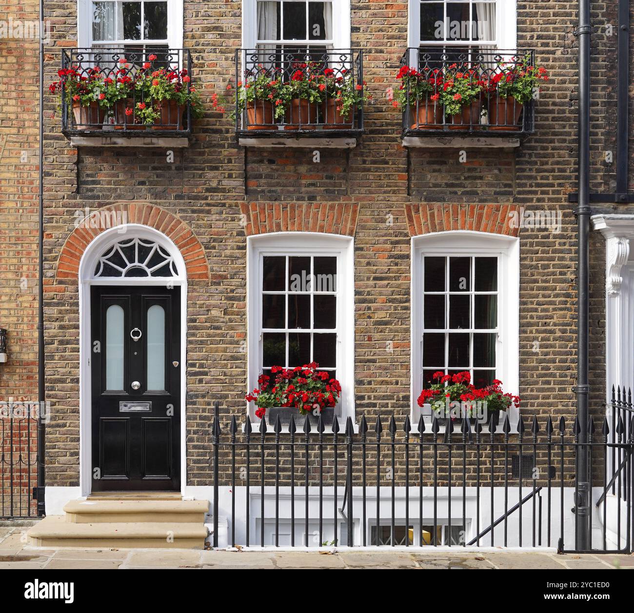 Vecchia casa cittadina in mattoni a Londra con gerani nelle finestre Foto Stock