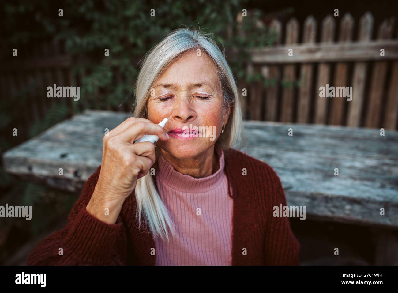 Le donne anziane si sentono malate, usando spray nasale per aiutare a congestione, peluria. Foto Stock