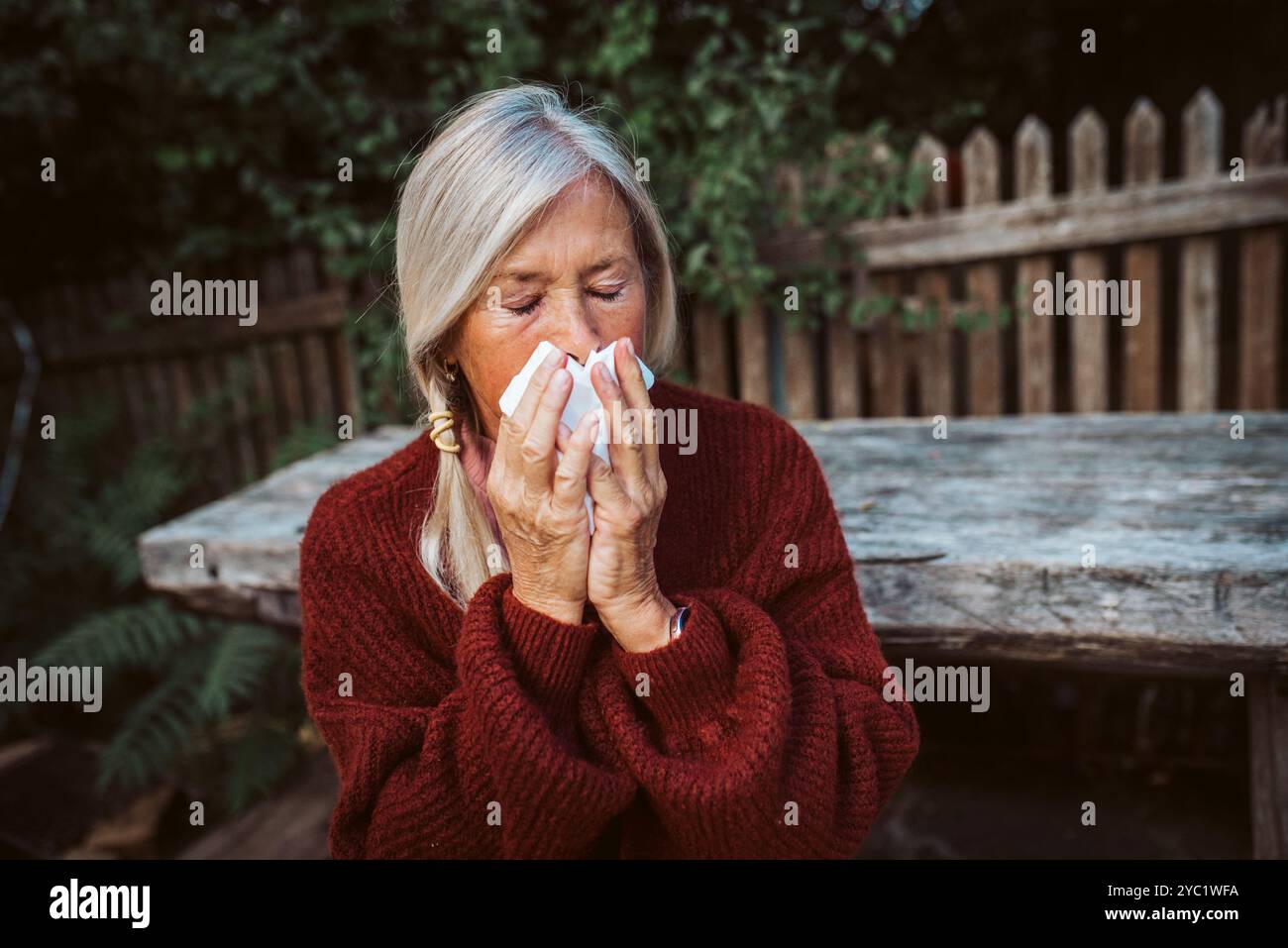Le donne anziane si sentono male, soffiando il naso che cola e chiuso nel tessuto e starnuto. Foto Stock
