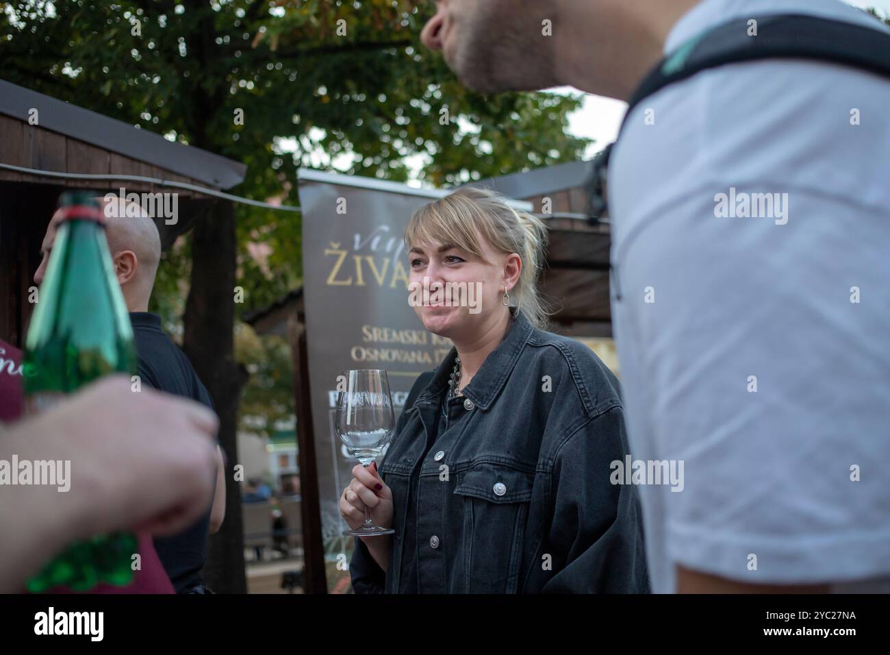 Serbia, 21 settembre 2024: Una donna assaggia il vino accanto allo stand di un produttore alla fiera del vino Sremski Karlovci (Grožđebal). Foto Stock