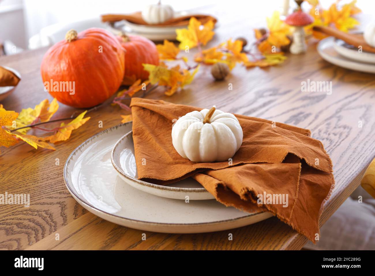 Tavolo festivo per l'autunno, l'autunno, Halloween o il giorno del Ringraziamento. Foglie cadute, zucche e tovagliolo sul piatto su sfondo di legno. Foto Stock