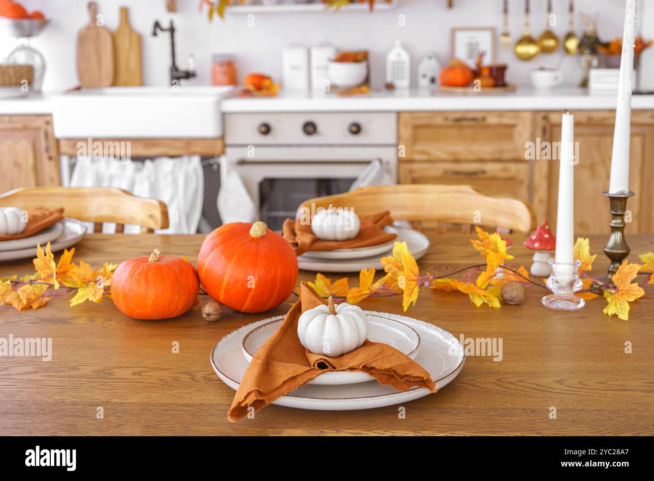 Il tavolo da pranzo è elegante e perfetto per le vacanze autunnali, Halloween o il giorno del Ringraziamento, con zucche arancioni, piatti con tovaglioli e foglie colorate Foto Stock