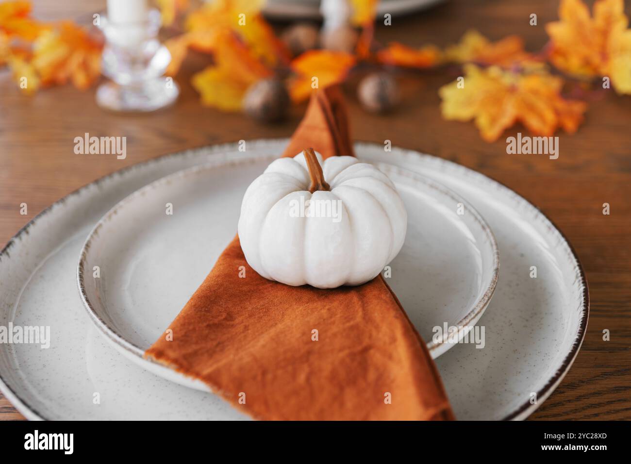 Autunno, autunno, Halloween o festa del Ringraziamento. Foglie cadute, zucche e tovagliolo sul piatto su sfondo di legno. Foto Stock