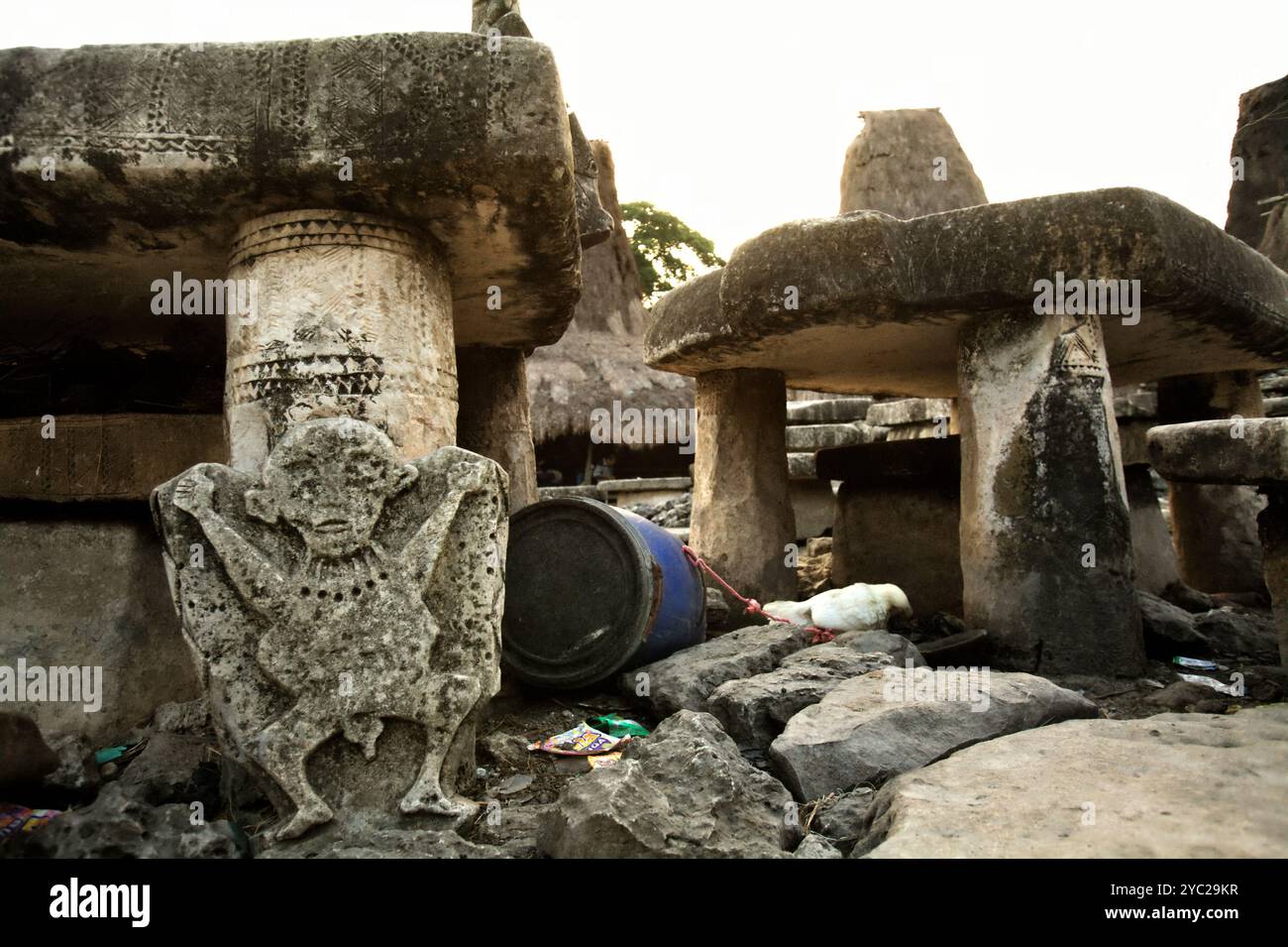 Scultura in pietra di una figura umana di fronte a un dolmen megalitico nel tradizionale villaggio di Tarung a Waikabubak, l'isola di Sumba, Indonesia. Foto Stock