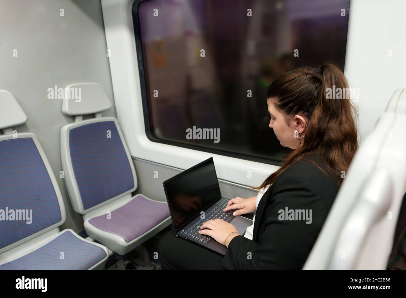 Giovane donna d'affari che lavora su un notebook mentre viaggia in treno Foto Stock