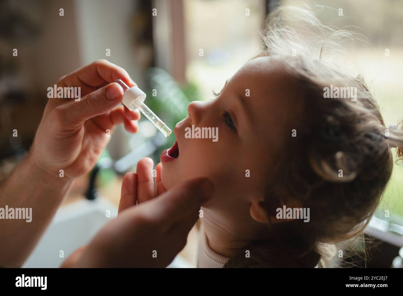 Padre che dà alla figlia la medicina con contagocce, sciroppo per tosse o medicina per la febbre. Ragazza malata con febbre e freddo a casa Foto Stock