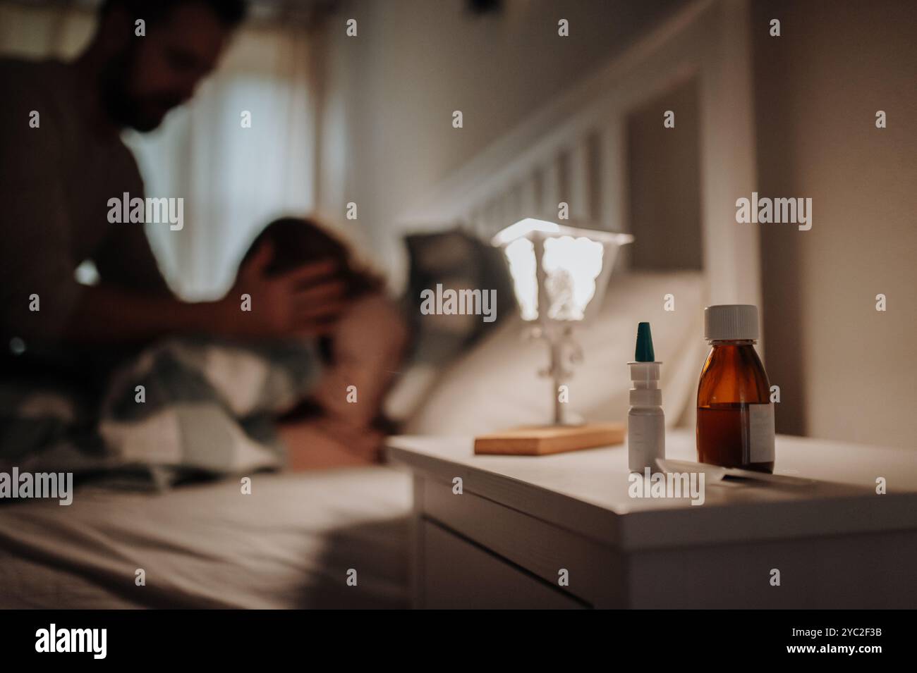 Primo piano sui farmaci sul comodino. Una ragazza malata con il freddo che giace nel letto, un padre che si prende cura di lei. Foto Stock