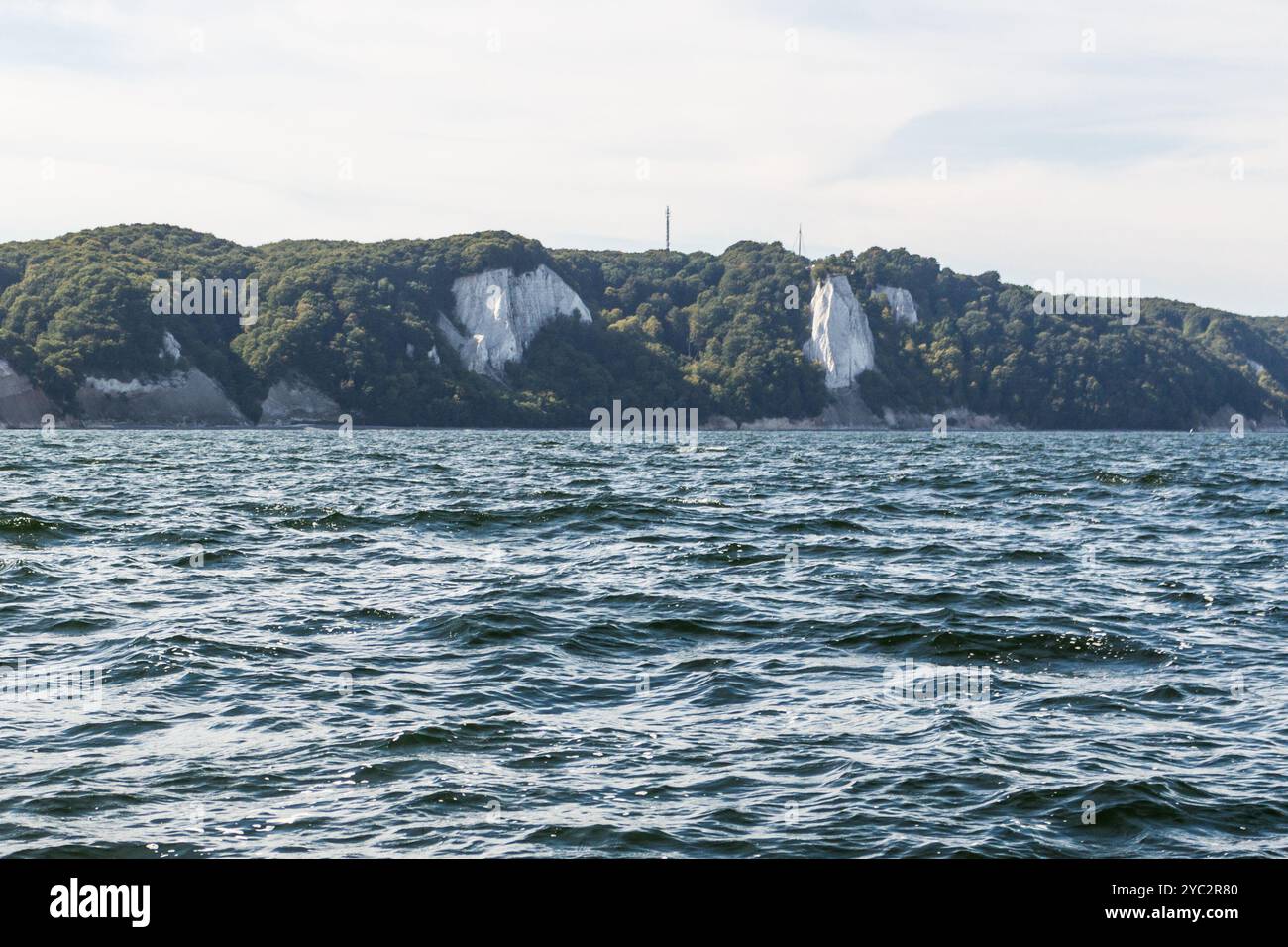 Le bianche scogliere di gesso sulla costa di Rügen si innalzano maestosamente sopra le acque blu scuro del Mar Baltico, circondate da una vegetazione lussureggiante sotto una luminosa Foto Stock