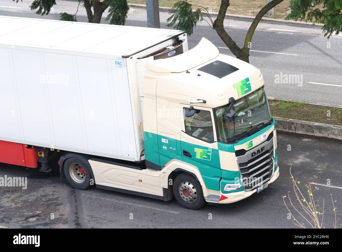 Il semirimorchio bianco e verde sta guidando su una strada in città Foto Stock