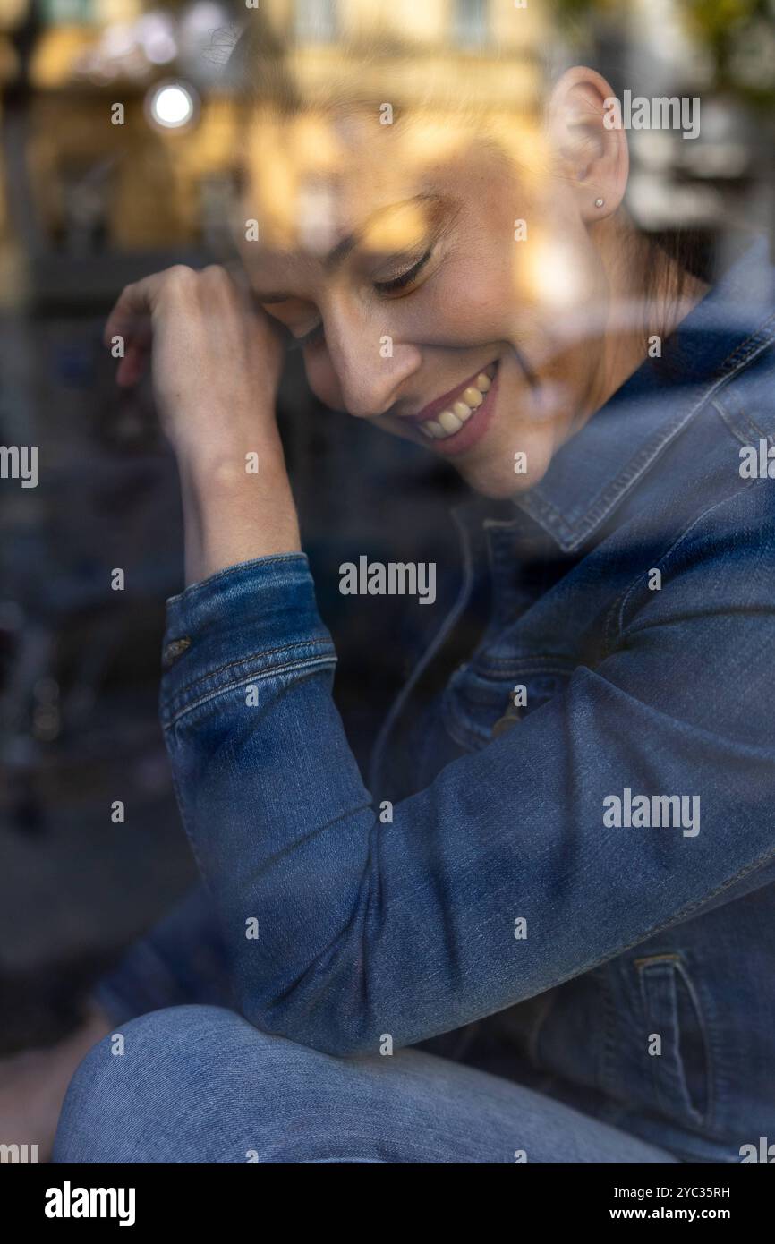 CREATIVE - Portrait Berlin, Deutschland - 19.10.2024: CREATIVE Eine Frau Model in Jeans Jacke und Jeans hose sitzt in einer Fensterbank eines Hauses i. Foto Stock