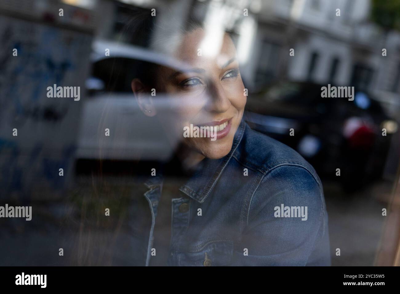 CREATIVE - Portrait Berlin, Deutschland - 19.10.2024: CREATIVE Eine Frau Model in Jeans Jacke und Jeans hose sitzt in einer Fensterbank eines Hauses i. Foto Stock