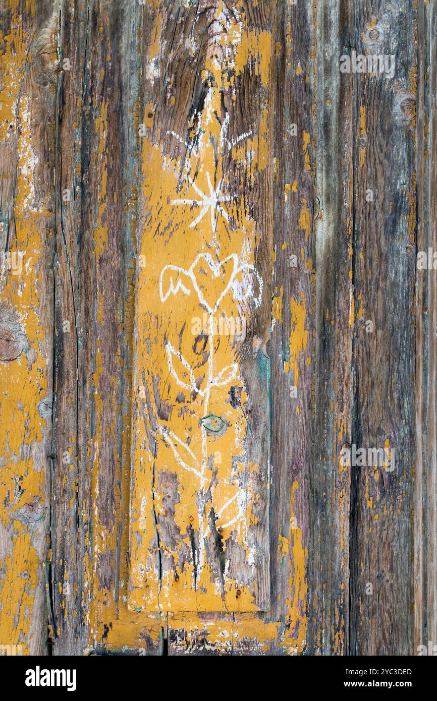 Dettaglio floreale in gesso su vernice giallo scaglie di una porta rustica in legno sulla tradizionale isola greca di Kastellorizo o Meis, Grecia, Europa Foto Stock