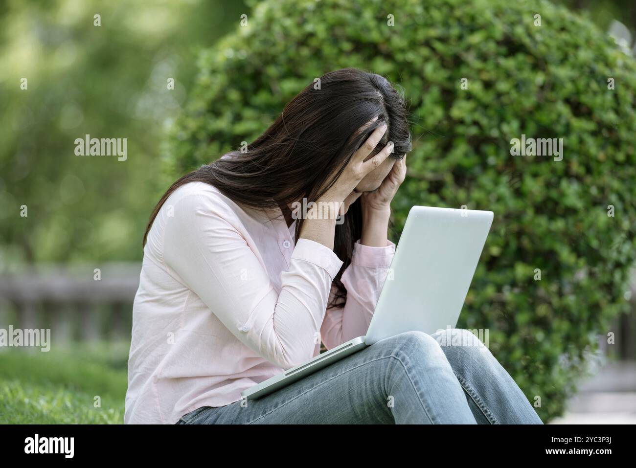 Donna asiatica seduta parco verde con computer portatile. Donna che lavora in un'azienda felice di un notebook che utilizza un notebook con le mani che digitano sulla tastiera Foto Stock