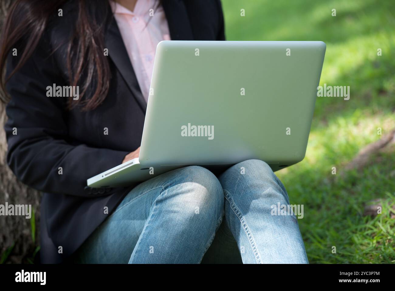 Donna asiatica seduta parco verde con computer portatile. Donna che lavora in un'azienda felice di un notebook che utilizza un notebook con le mani che digitano sulla tastiera Foto Stock