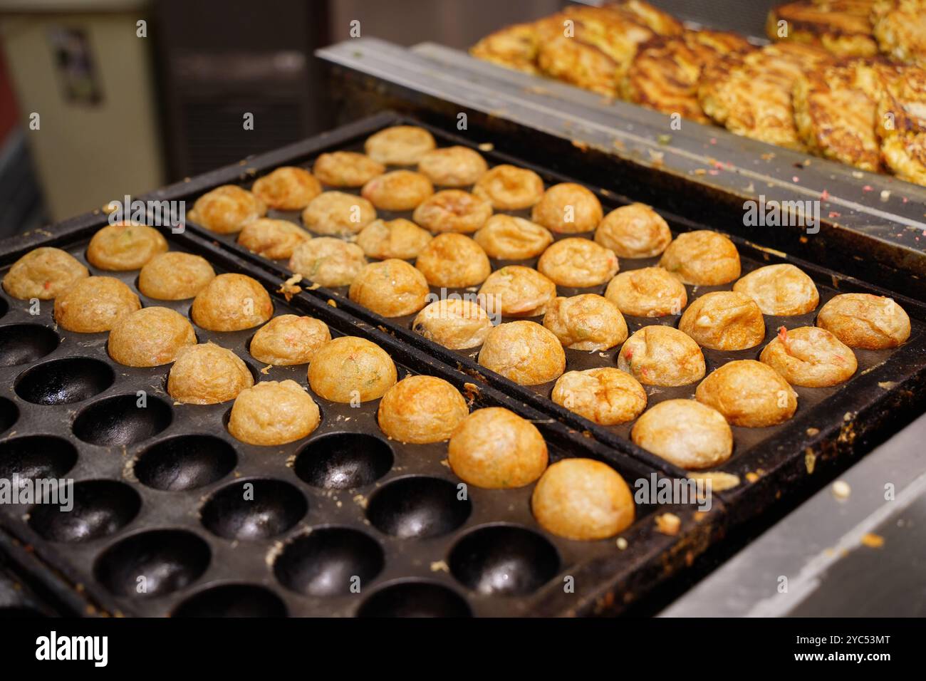 Il Takoyaki è un piatto giapponese preparato mettendo il polpo in una pastella di farina e cuocendolo Foto Stock