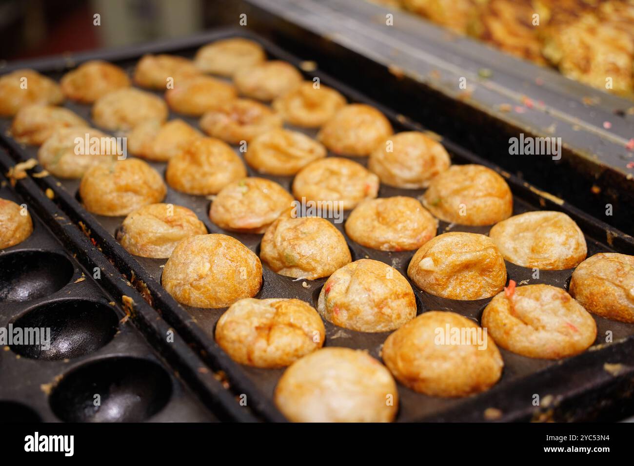 Il Takoyaki è un piatto giapponese preparato mettendo il polpo in una pastella di farina e cuocendolo Foto Stock