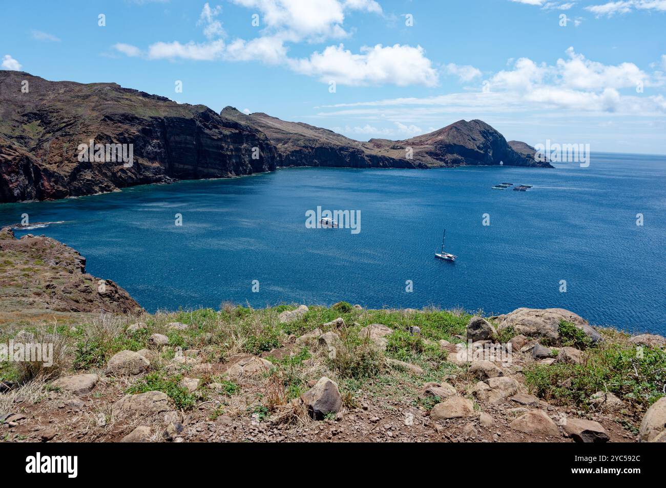 Barche che navigano lungo la spettacolare costa di Vereda da Ponta de São Lourenco, con scogliere aspre e acque blu brillanti Foto Stock