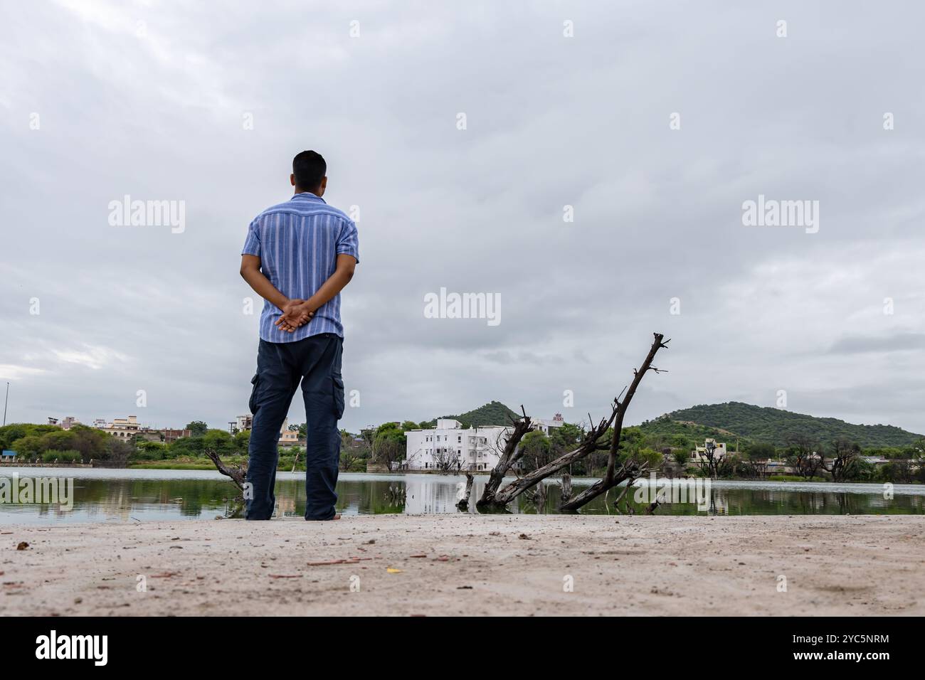 giovane uomo che guarda il lago incontaminato e calmo con un cielo spettacolare al mattino Foto Stock