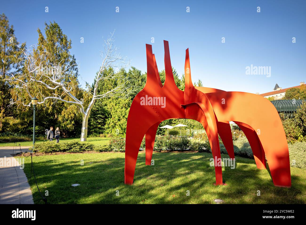 WASHINGTON DC, Stati Uniti: Alexander Calder's Cheval Rouge, una vivace scultura rossa realizzata in lamiera e vernice, si erge in primo piano nella National Gallery of Art Sculpture Garden. Creato nel 1974, questo pezzo dinamico è una delle opere iconiche di Calder, che mostra il suo stile unico di forme geometriche astratte in un ambiente pubblico all'aperto a Washington, DC. Foto Stock