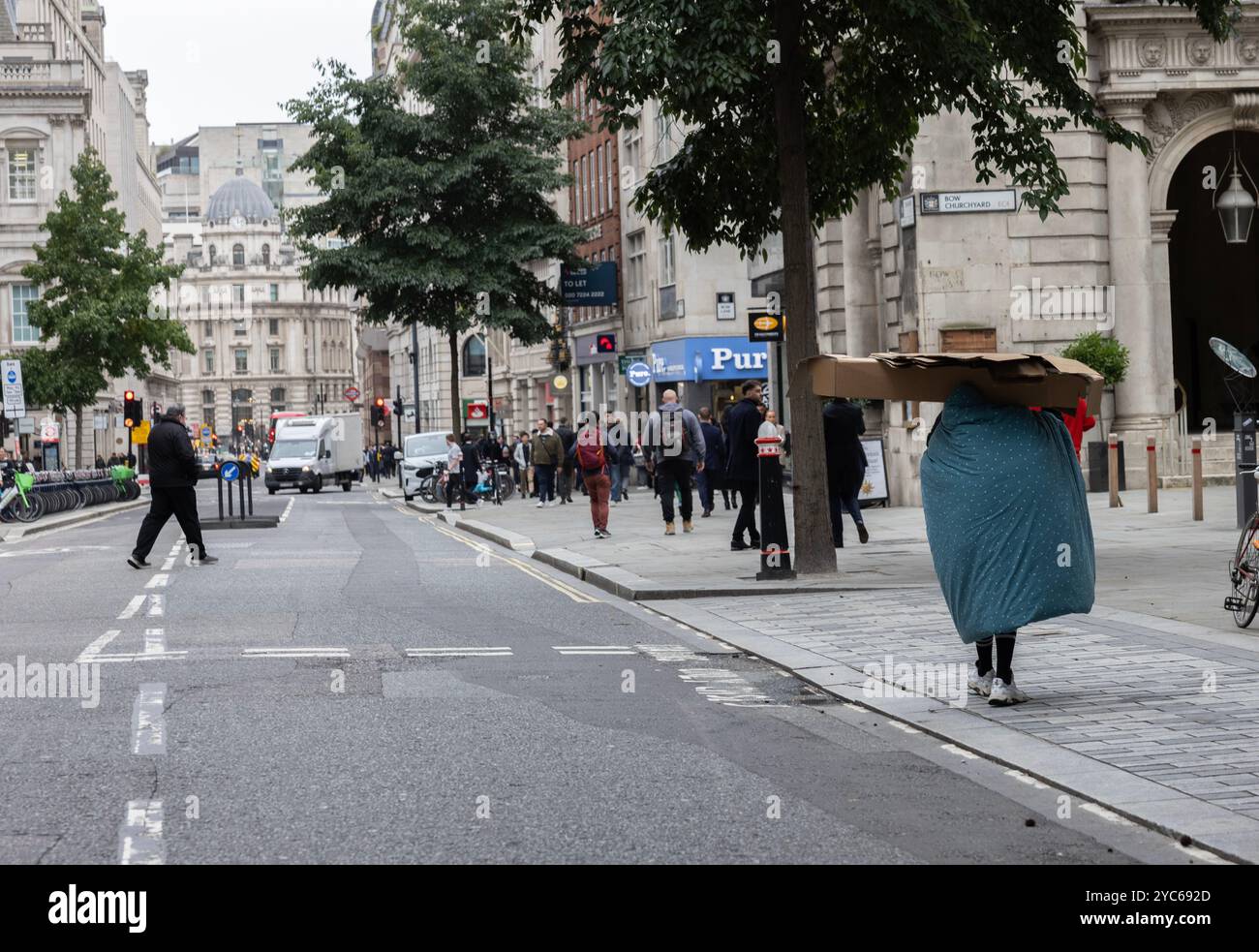 Senzatetto rude Sleeper porta la sua abitazione di cartone e il sacco a pelo sulle spalle lungo Cheapside, City of London, Inghilterra, Regno Unito Foto Stock