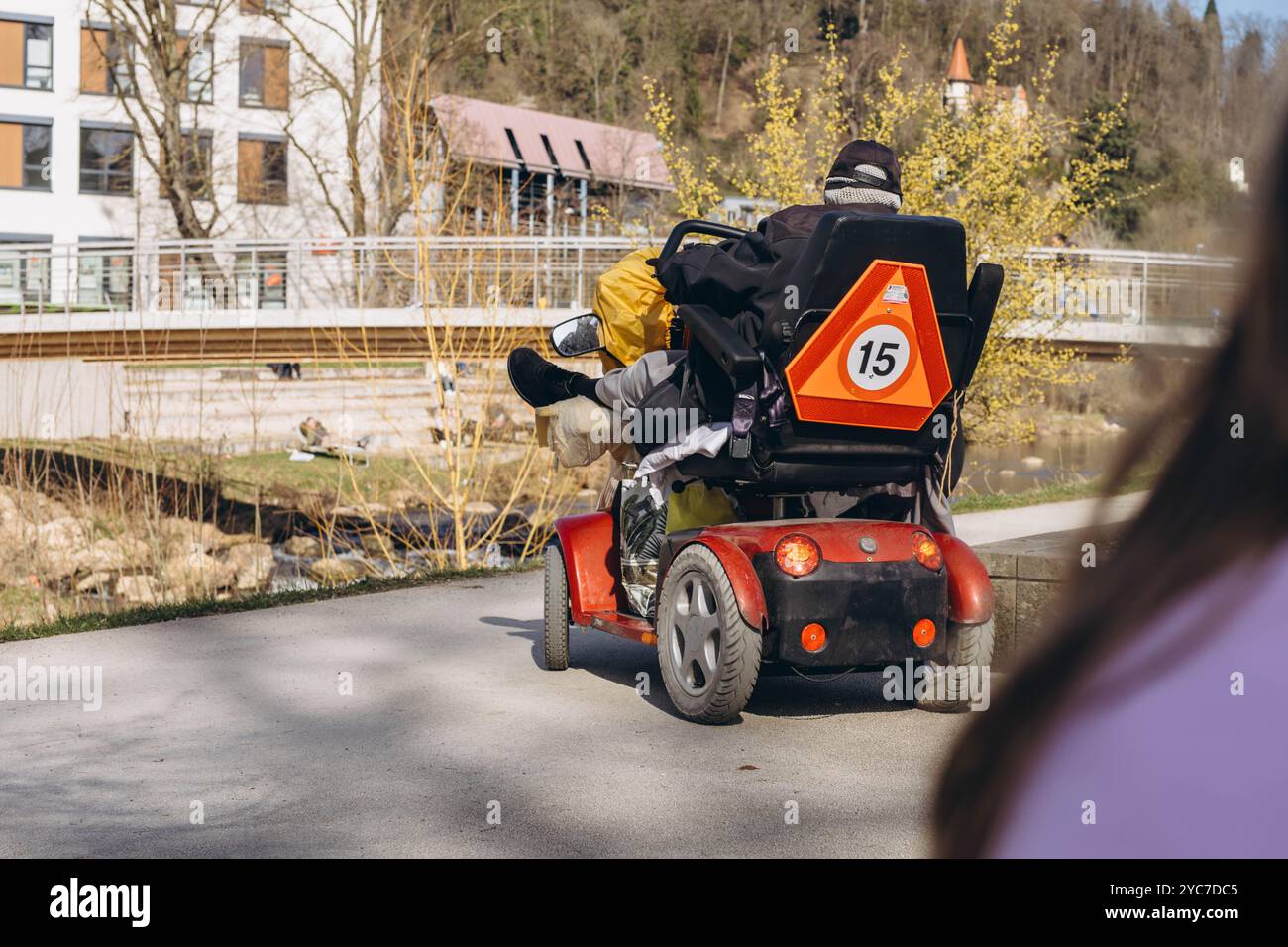 Persona in uno scooter specializzato per disabili, che guida attraverso un parco. Foto di alta qualità Foto Stock