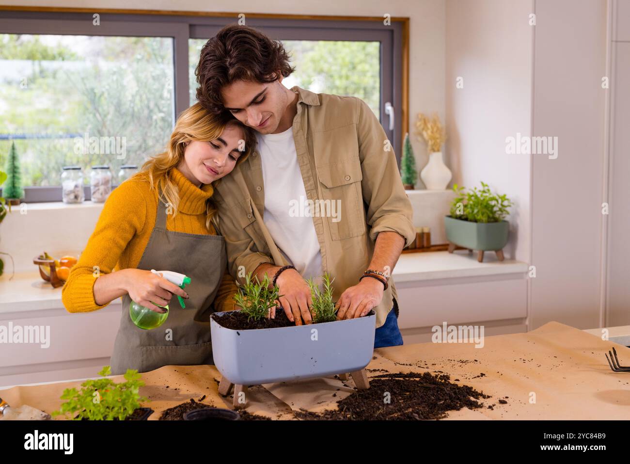 Coppia che si gode il giardinaggio al coperto insieme, piantare erbe in piantatrice da cucina, a casa Foto Stock