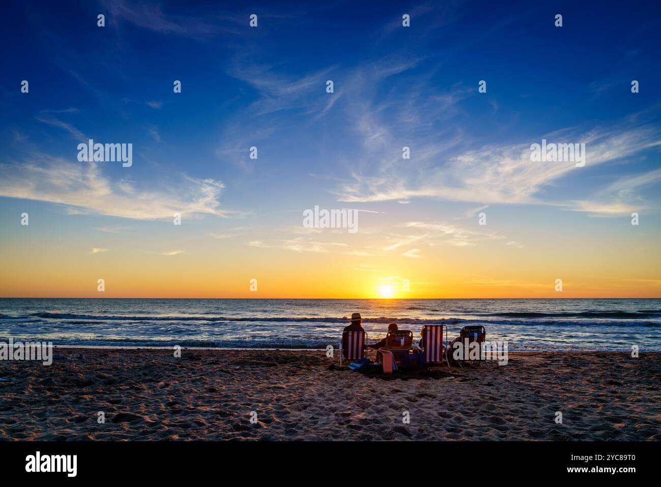 La famiglia а sta guardando il tramonto su una spiaggia di Venice, Florida Foto Stock