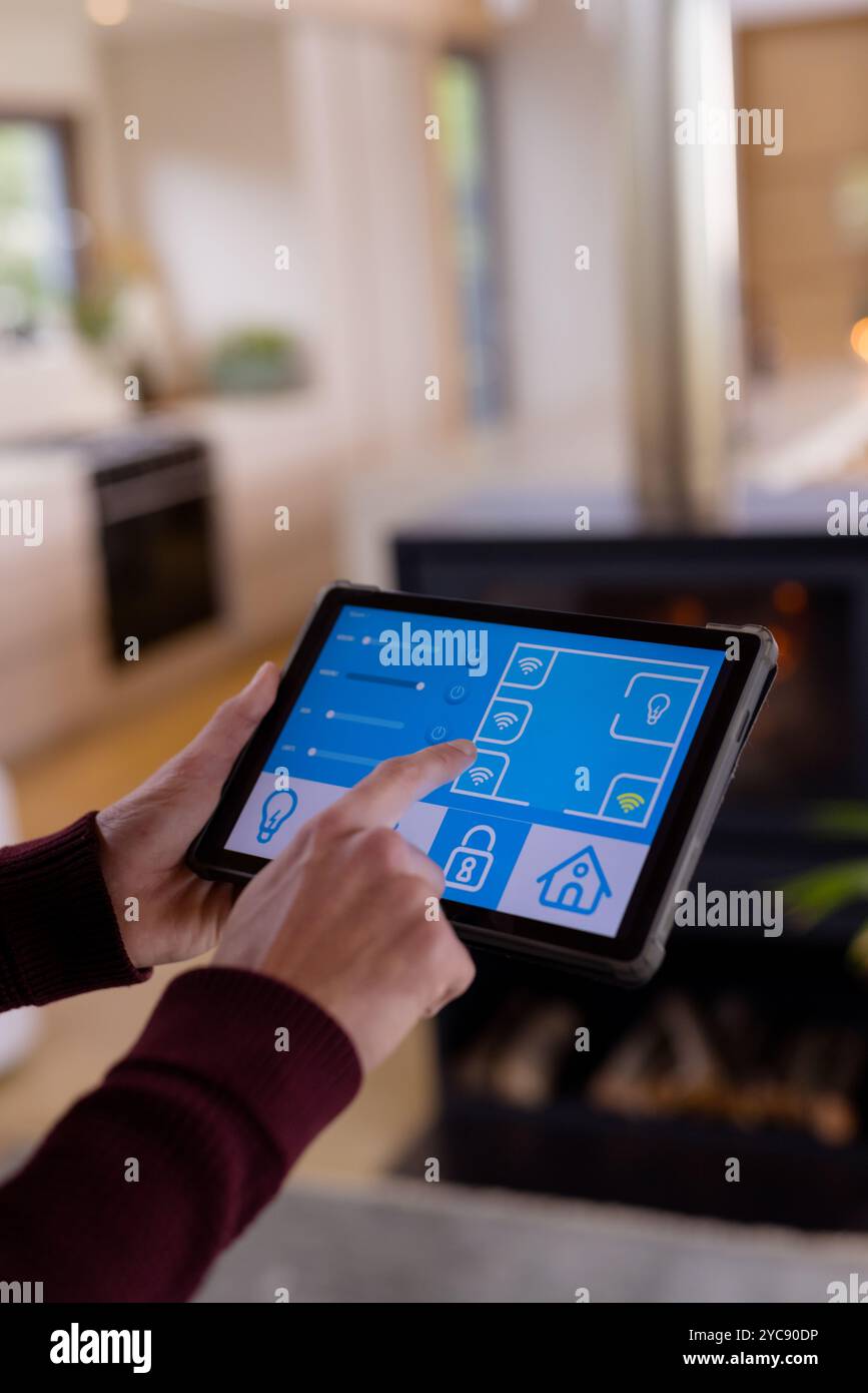 Natale, controlla i dispositivi domestici intelligenti utilizzando un tablet in un salotto accogliente Foto Stock