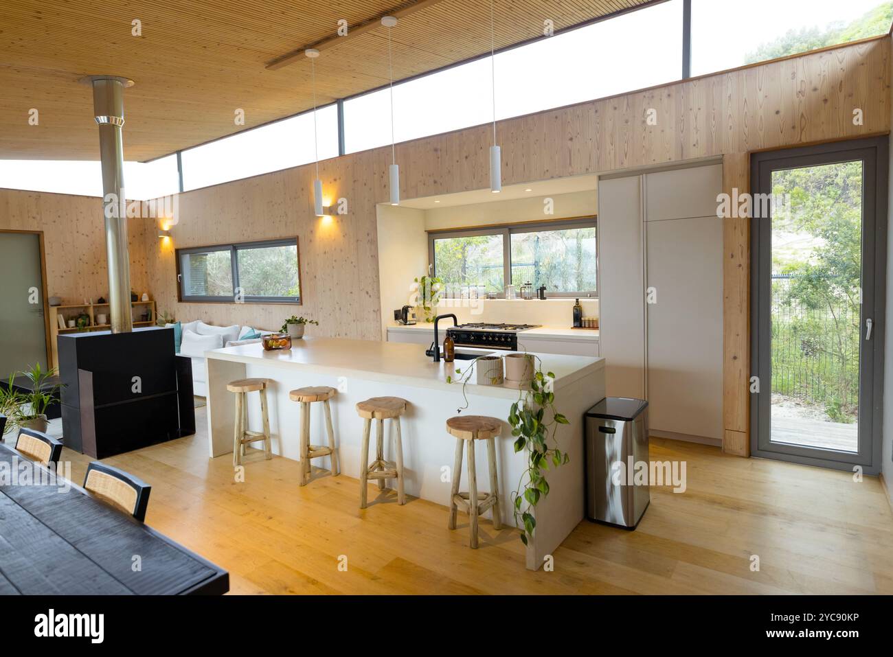 Cucina moderna con accenti in legno e sgabelli da bar in uno spazio luminoso e aperto, a casa Foto Stock