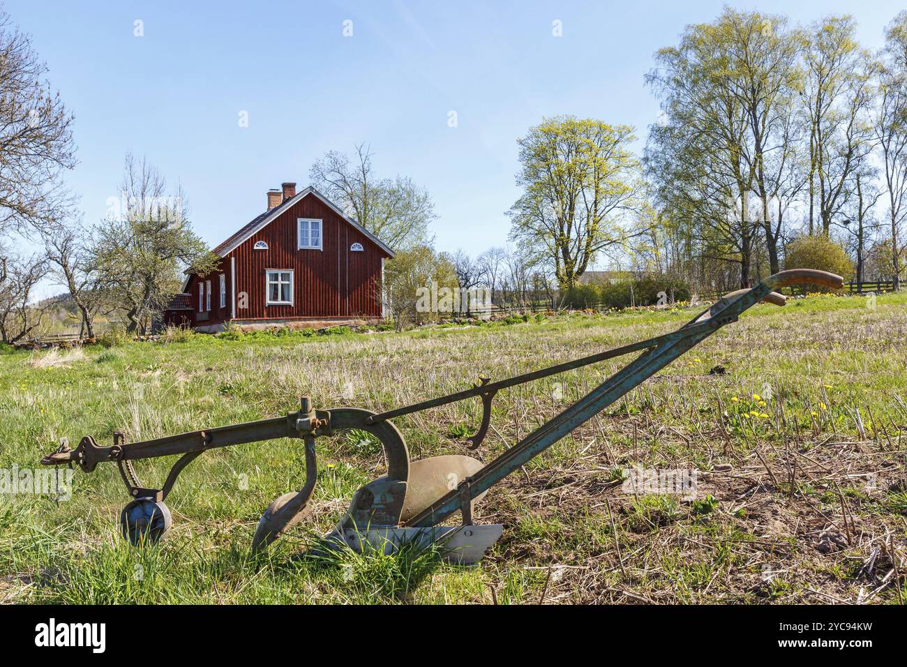 Il vecchio cavallo arare il campo con un rosso cottage Foto Stock