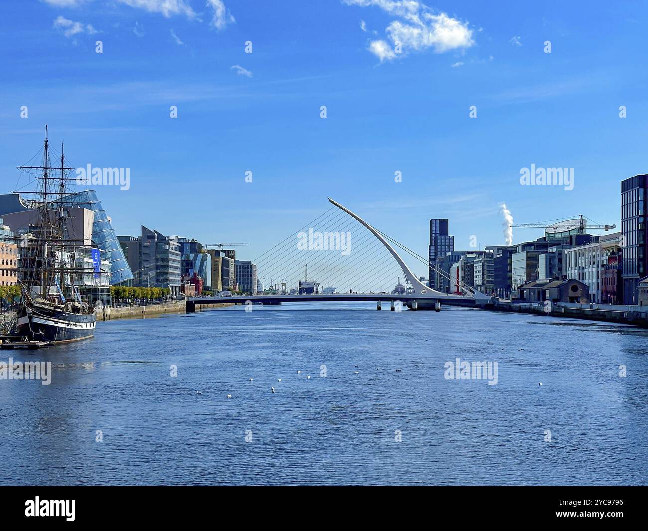 Moderna vista sul fiume con ponte e barca a vela sotto un cielo azzurro, Dublino, Irlanda, Europa Foto Stock