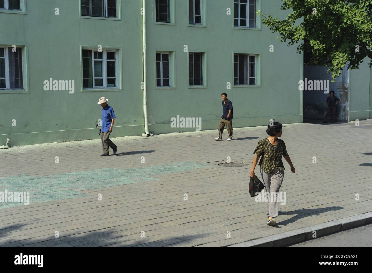 08.08.2012, Pyongyang, Corea del Nord, Asia, i pedoni camminano su un ampio e altrimenti deserto marciapiede lungo edifici residenziali a più piani nel c Foto Stock