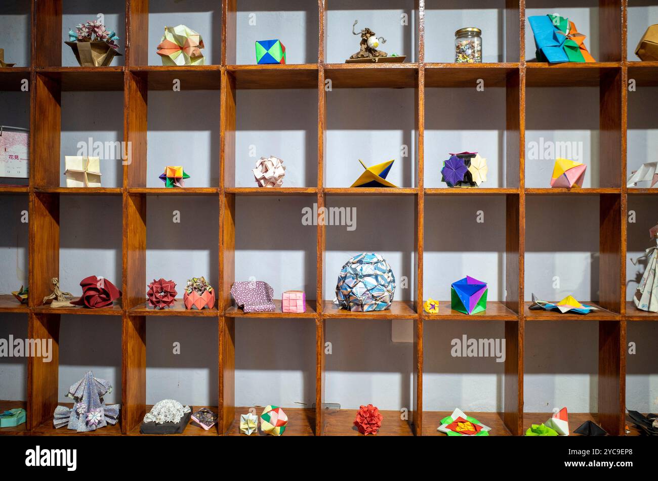 Oggetti origami colorati e oggetti di artigianato esposti su un ripiano di legno per la carta da parati. Foto Stock