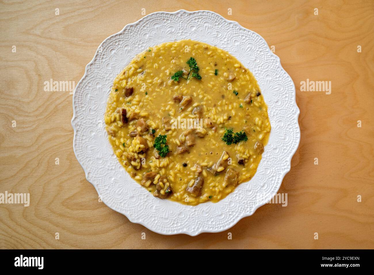 Piatto completo di autentico risotto ai funghi italiani servito su porcellana bianca ornata. Piatto di riso cremoso fatto in casa con funghi e prezzemolo. Semplice elegante Foto Stock