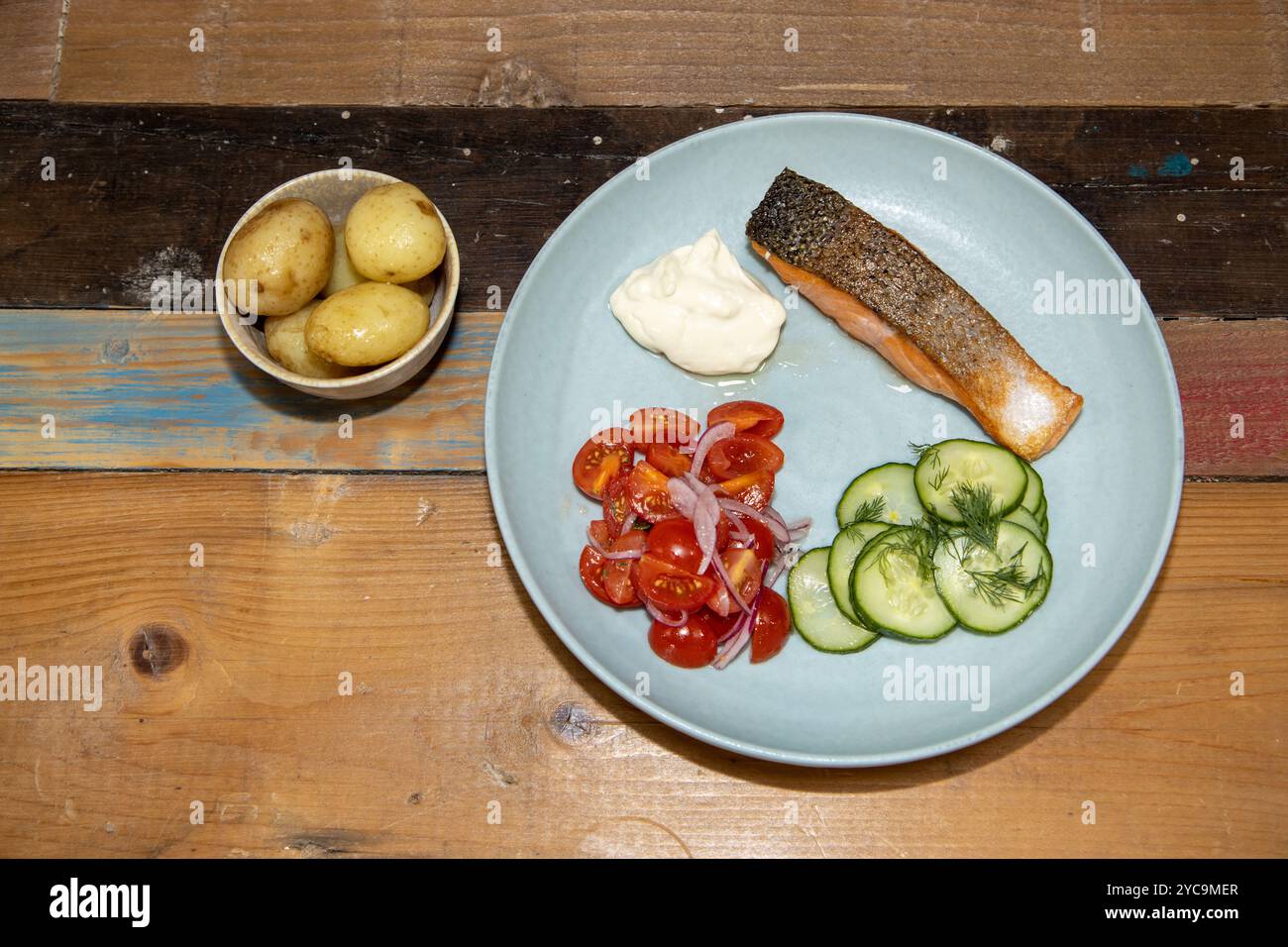 Un delizioso piatto di salmone e insalata servito con contorno o patate novelle in cucina su un tavolo di legno o un piano di lavoro Foto Stock