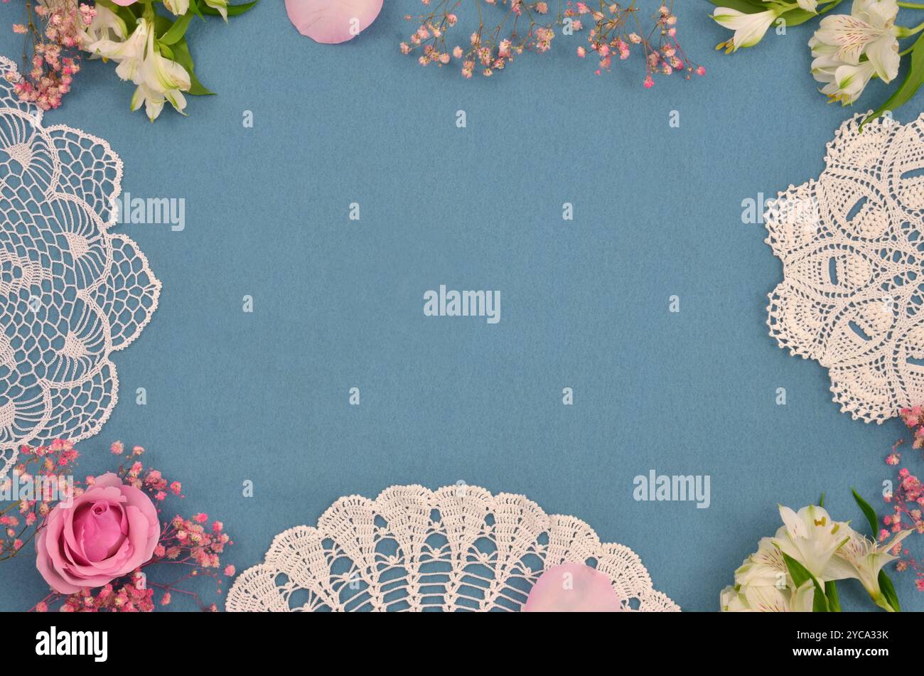 Crochette vintage bianche e fiori rosa su sfondo blu con posto vuoto per riempire di contenuto. Vista dall'alto. Foto Stock