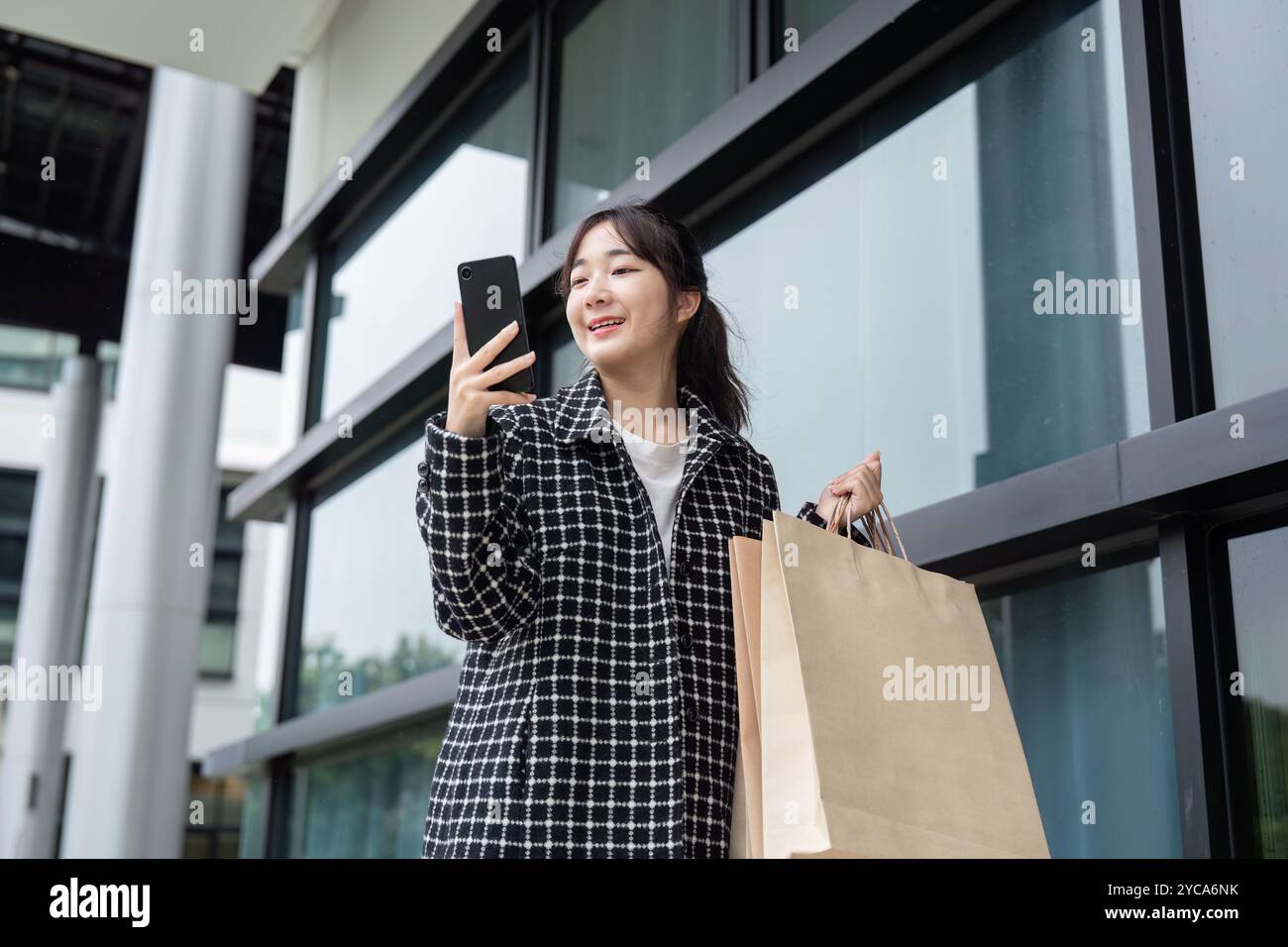 Joyful Shopper celebra le offerte del Black Friday con smartphone Foto Stock